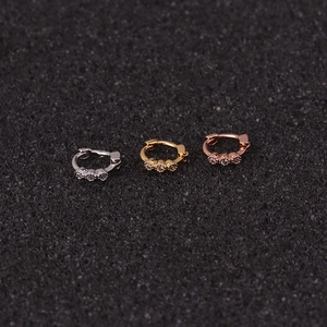 Macro shot of mini cartilage ear cuffs in silver, gold, and rose gold with zircon stones