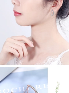 Detail view of crescent moon and star earrings with blue crystals in silver and rose gold