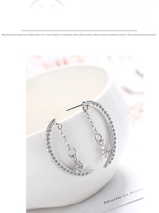 Close-up of crescent moon earrings with silver stars and sparkling zircon pendants