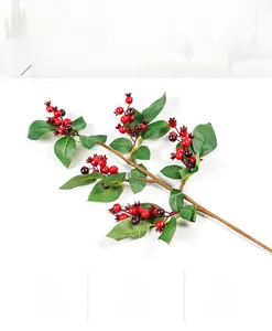 Detailed close-up of artificial pomegranate branch with red berries and green leaves