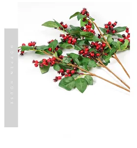 Detailed view of artificial red berry branches with realistic green leaves and wood texture