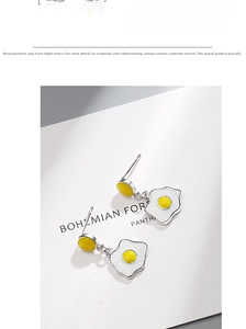Detailed view of creative fried egg stud earrings with white and yellow enamel texture