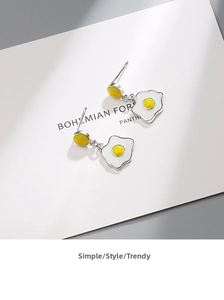 Detail of creative fried egg dangle earrings with silver metal edges and enamel finish