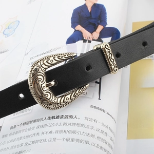 Vintage style black skinny leather belt with engraved gold buckle on magazine background