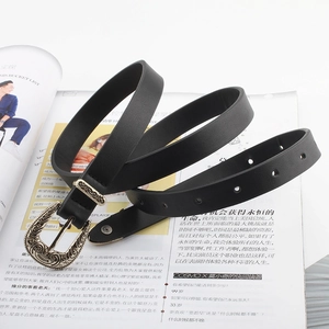 Vintage skinny black leather belt with ornate gold floral buckle on fashion magazine