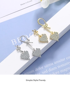 Close-up of heart-shaped drop earrings with pavé crystals in gold and silver finishes