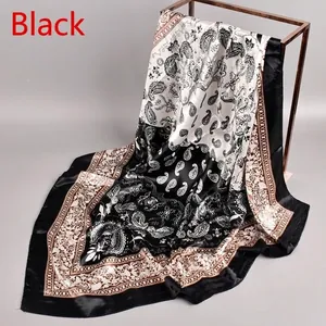 Close-up of black and brown paisley silk satin square scarf draped on a metal rack
