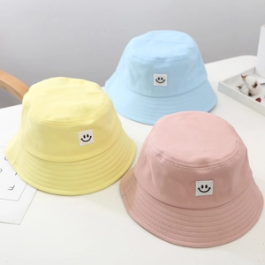 Detailed arrangement of children's cotton bucket hats in yellow, light blue, and pink colors