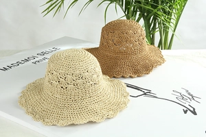 Dettaglio cappello di paglia fatto a mano con tesa ondulata nei colori beige e kaki
