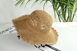 Dettaglio del cappello in paglia all'uncinetto con motivo traforato e bordo ondulato
