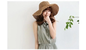 Dettaglio della trama del cappello di paglia e elegante abito lungo verde senza maniche