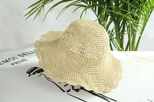Dettaglio cappello di paglia beige all'uncinetto con trama traforata e tesa ondulata