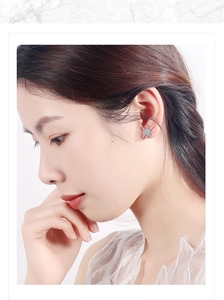 Close-up of asymmetric silver star stud earring with sparkling cubic zirconia on model ear