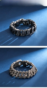 Detail of vintage carved stainless steel curb chain bracelet with intricate patterns
