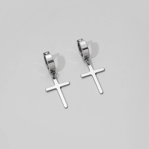 Macro view of polished stainless steel huggie hoop earrings with cross pendants