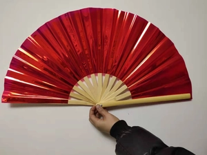 Close-up of a 33cm red laser PVC kung fu fan with natural bamboo ribs held by a hand