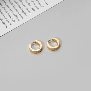 Macro detail of gold matte round hoop earrings on a minimalist aesthetic background