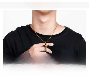 Detail of stainless steel cross necklace on male model with rope chain and bicolor finish