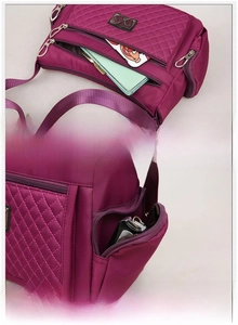 Detail showing multiple functional front and side zipper pockets on purple quilted nylon bag