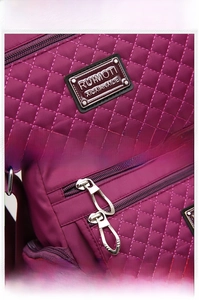 Detailed macro view of diamond-quilted purple nylon bag with premium metal logo and zippers