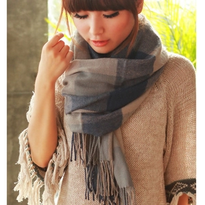 Detail of grey-blue plaid scarf with long fringe showing soft cashmere-like texture