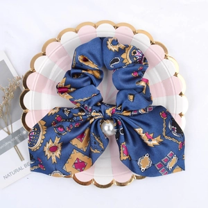 Blue satin silk scrunchie with vintage patterns and a pearl pendant on a decorative plate