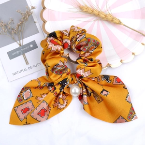 Close-up of yellow geometric print ribbon scrunchie with a large pearl pendant detail