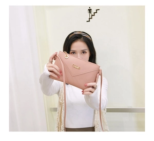 Detail of pink leather envelope bag with gold logo and leaf zipper pull charm