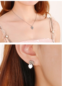 Detail of silver jewelry set with Roman numeral round pendants and small heart charms