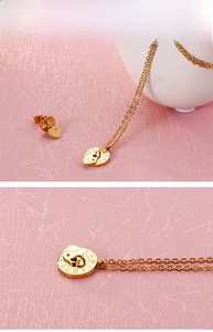 Close-up of gold stainless steel necklace set with Roman numeral and heart love charms