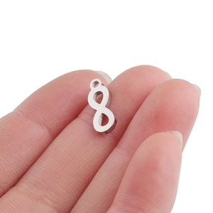 Polished silver infinity symbol pendant in stainless steel held between fingers