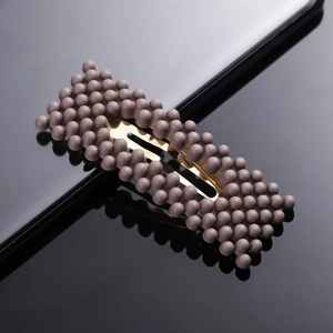 Detail shot of a brown matte finish pearl hair clip with metal BB grip on a sleek surface