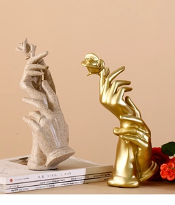 Detailed view of hand-holding-rose resin sculptures in sandstone and gold finishes