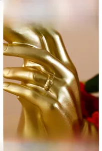 Close-up of a gold ring with three embedded gems on a resin hand sculpture detail