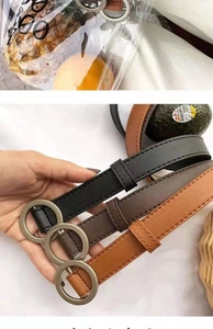Detail view of three PU leather belts in black, dark brown, and tan with round buckles