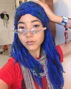 Close-up of stylish rimless diamond-cut sunglasses with a blue woolen dreadlock hat