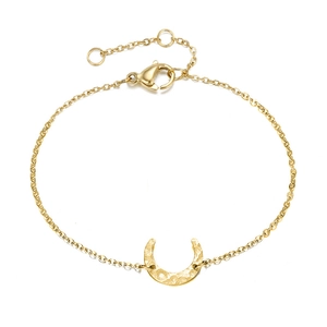 Close-up of golden crescent moon bracelet with hammered texture and delicate cross chain