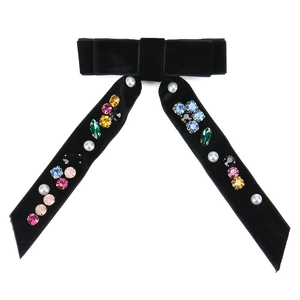 Detail of black velvet bow brooch with colorful gemstones and white pearls for women