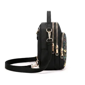 Waterproof black nylon crossbody bag with three zipper layers and gold hardware detail