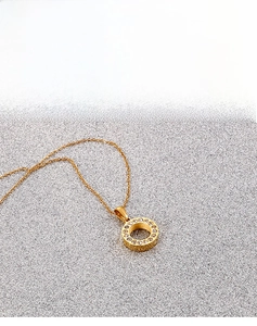 Close-up of gold-plated circular pendant with sparkling pavé white zircon stones