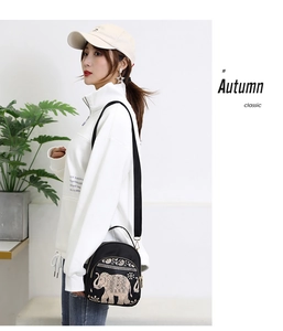 Detail of black crossbody bag with golden elephant embroidery and long shoulder strap