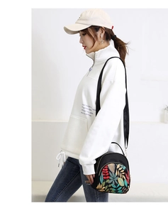 Detailed side view of a black water-resistant nylon backpack with colorful leaf embroidery