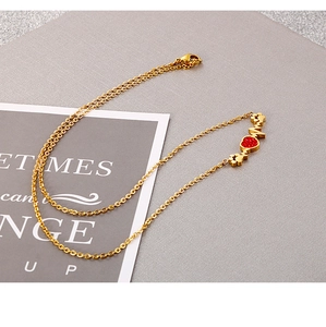 Détail d'un collier en titane doré avec pendentif en forme de cœur rouge et patte