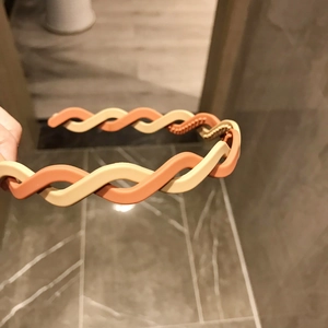 Close-up of twisted weave headband in orange and beige with non-slip inner teeth