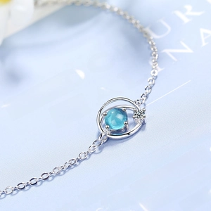 Elegant silver bracelet with a blue planet pendant and zircon accents on blue background