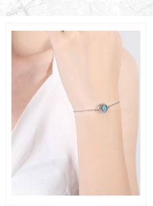 Close-up of a silver dream planet bracelet with a blue bead on a woman's wrist