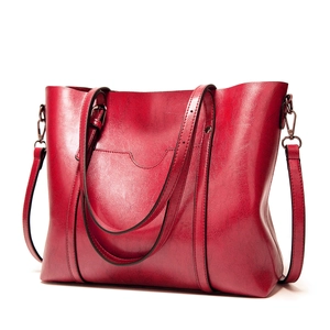 Détail d'un grand sac cabas rouge vintage avec cuir brillant et boucles en métal argenté