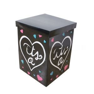 Détail d'une boîte cadeau noire pour baby shower avec cœur blanc et motifs colorés