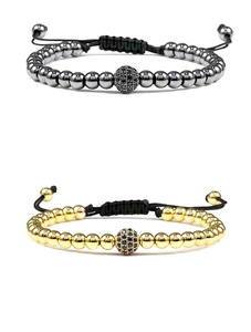 Macro detail of braided macramé bracelets with gold and hematite beads and zircon charm