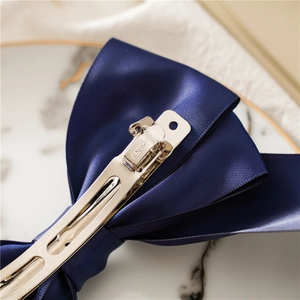 Detailed macro view of navy satin bow hair clip featuring a silver French spring metal fastener